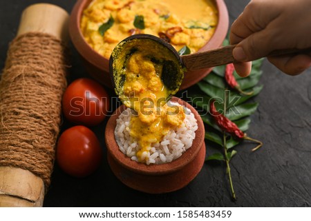 Prawn mango curry recipe and rice Chemmeen Manga shrimp in coconut milk. Spicy Kerala fish curry on dark black background South India. Top view popular Indian seafood, non veg food side dish for appam