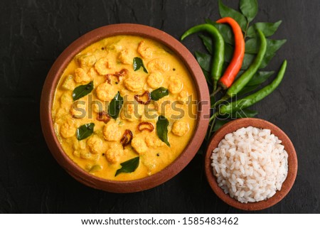 Prawn mango curry recipe and rice Chemmeen Manga shrimp in coconut milk. Spicy Kerala fish curry on dark black background South India. Top view popular Indian seafood, non veg food side dish for appam