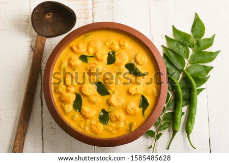 Prawn mango curry recipe, Chemmeen Manga shrimp in coconut milk. Spicy Kerala fish curry on white background South India. Top view popular Indian seafood, non veg food side dish for rice, appam