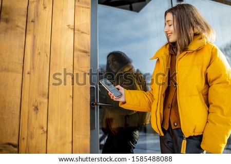 Woman locking smartlock on the entrance door using a smart phone. Concept of using smart electronic locks with keyless access Royalty-Free Stock Photo #1585488088