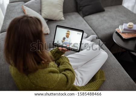 Woman talking with a doctor online using digital tablet, feeling bad at home. Concept of telemedicine and patient counseling online Royalty-Free Stock Photo #1585488466