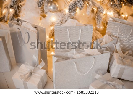 gifts boxes and packages under the luxurious festive decor of the Christmas tree with garlands for the festive holiday. Background of a happy new year and the atmosphere of comfort.
