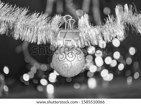 Christmas ornaments concept. Ball ornament hang on shimmering tinsel. Pick colorful decor for christmas tree. Tinsel with pinned christmas ornament on defocused garland lights background.