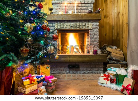 Christmas evening. Christmas tree and christmas gift boxes and candles before cozy burning fireplace.