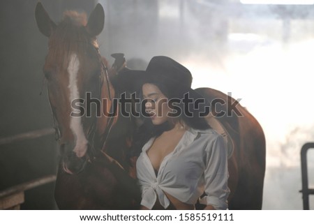 Beautiful woman spending time with her horse in barn at farmland