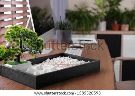 Beautiful miniature zen garden and computer on wooden table in office Royalty-Free Stock Photo #1585520593