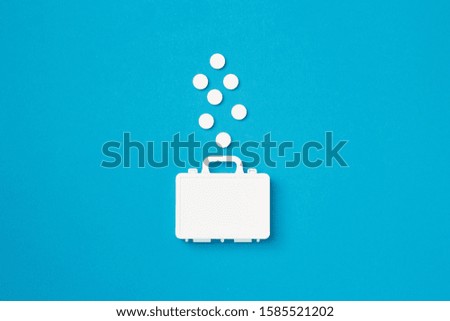 Suitcase with pills on a blue background. Creative idea for drugstore, online pharmacy, health behaviors and pharmaceutical company business concept. Flat layout.