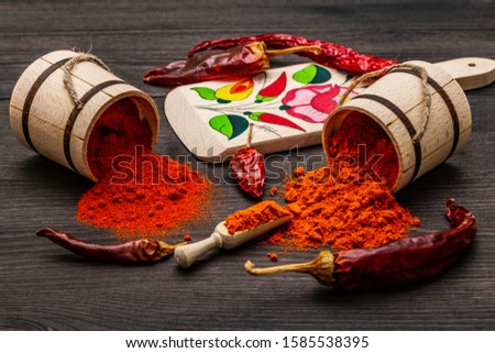 Magyar (Hungarian) red sweet and hot paprika powder. Traditional pattern on a cutting board, different varieties of dry pepper. Black wooden background, close up Royalty-Free Stock Photo #1585538395