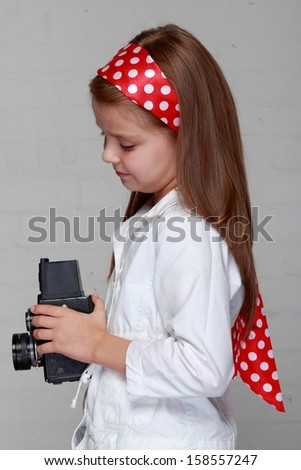 Image of lovely emotional young girl with beautiful hair holds a vintage camera