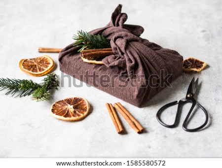 Eco-friendly fabric reusable gift packaging with fir brunch, cinnamon stick and dry orange slice. Christmas   reusable sustainable gift wrapping alternative.  Zero waste concept. Copy space
