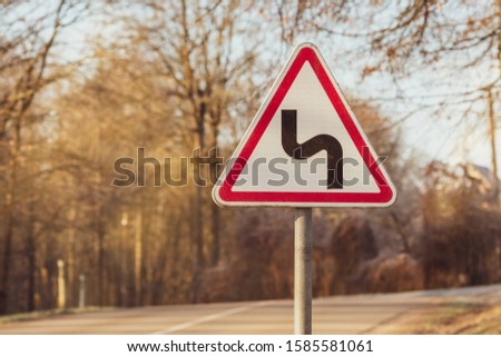 Curved road traffic sign on dangerous forest road 