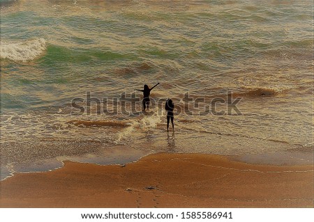 A closeup shot of people getting ready to swim in the splashing waves of the ocean