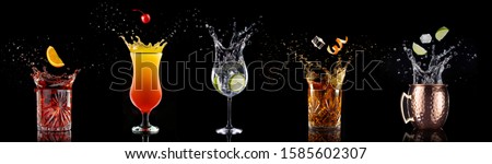 fruit falling into a collection of splashing cocktails isolated on black background Royalty-Free Stock Photo #1585602307