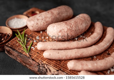
Raw grilled sausages with spices and rosemary, on a stone table, cooking concept