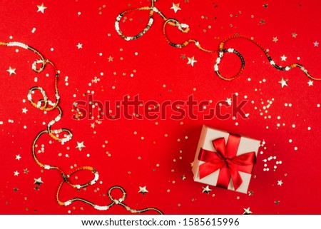 Gift box on trendy red background with sparkles. Flat lay style