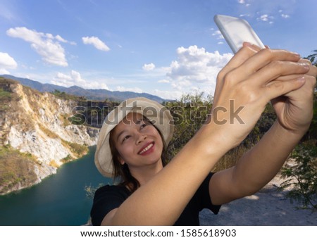 Asian female tourists are taking pictures of themselves at tourist attractions using a smartphone.