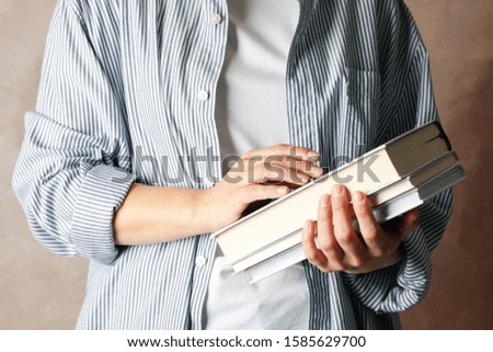Woman holding books against brown background, close up