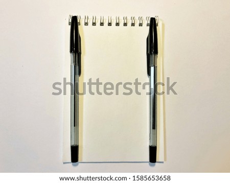 opened notebook paper with black pen on white desk, copy space