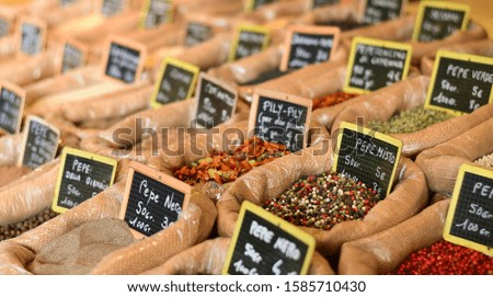 farmers market for spices, aromatic herbs and dried fruits in Italy. the names of herbs and spices in Italian and the price in euros are written on black plates