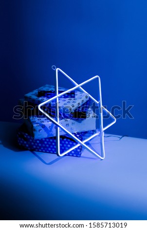 Chanukah Hanukkah presents with neon Star of David. Hip and trendy Hanukkah wrapping paper and decoration to celebrate the Jewish high holiday of Chanukah in December.