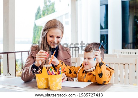 mom and young boy draw colored pencils