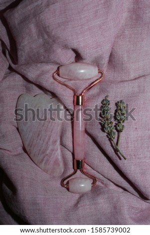 Face roller on pink cotton background. Face massager flat lay. Vertical photo.