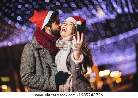 Happy young loving couple making selfie and smiling while standing Christmas background