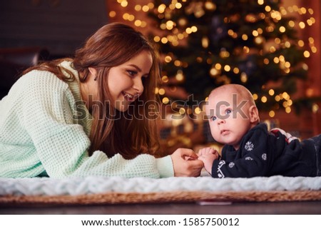 Mother with her child together in christmas decorated room.