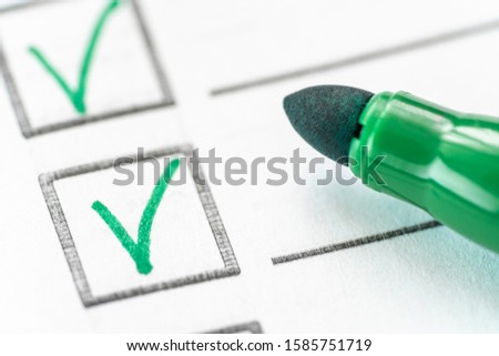 check mark and green marker on white background. Checklist, quality service survey concept. Macro photography