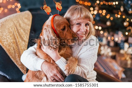 Grandmother indoors with dog in christmas decorated room.