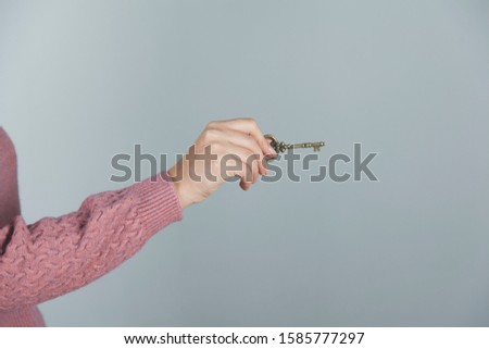 woman hand holding vintage key on gray background