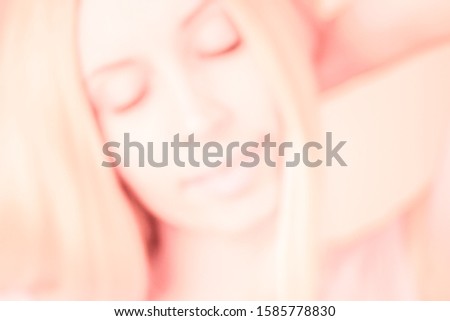 Happy smiling young blond woman portrait with closed eyes, pink tone, blurred