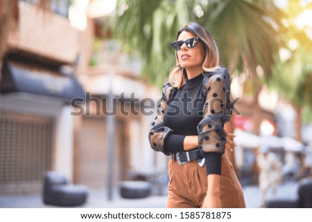 Young beautiful woman wearing sunglasses smiling happy and confident. Standing and walking at town street