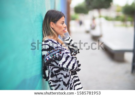Young beautiful girl smiling happy and confident leaning on the wall at the town street, standing with a smile on face