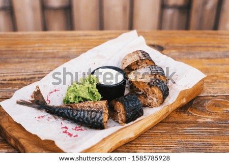Smoked mackerel cut into pieces on a wooden board