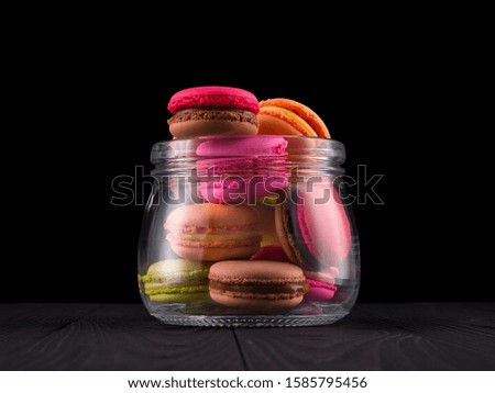 Jar of french colorful macaroon or macaron on wooden table isolated on black background with clipping path