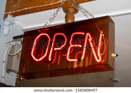 A neon sign hanging from a shops ceiling saying OPEN