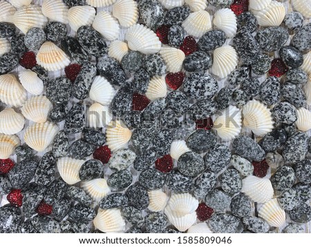Wooden background from seashells and stones. Red hearts of red color for St. Valentine's Day. Romantic background.