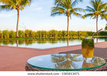 A palm tree reflecting in a glass table with a glass of a refreshing drink on the top in Phnom Penh in Cambodia
