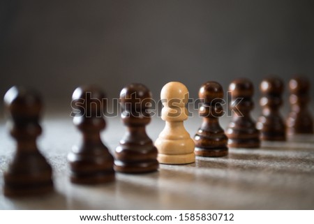 Authenticity and uniqueness concept. White pawn standing in a line, selective focus.
