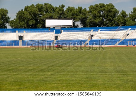 a man on a lawn mower cuts green grass at a football stadium