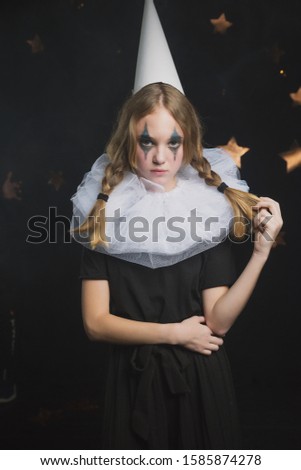 

sad circus artist, clown girl in black and white outfit with a cap on her head