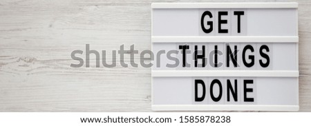 'Get things done' words on a modern board on a white wooden background, top view. Overhead, from above, flat lay. Space for text.