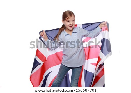 Studio image of a cute cheerful little girl with a happy smile, holding a large flag of England on a white background/Joyful girl with the flag the United Kingdom