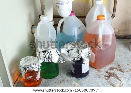 Variety in mysterious chemicals stored improperly and unlabeled in jugs and jars under a sink Royalty-Free Stock Photo #1585889899