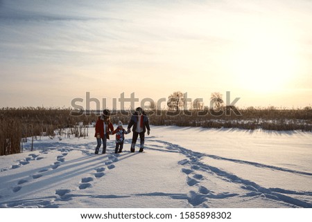 walking family in the winter. active people outdoors on the sunset