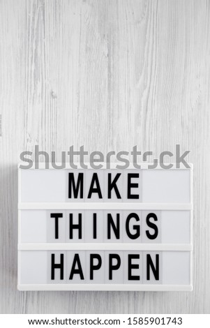 'Make things happen' words on a modern board on a white wooden background, top view. Overhead, from above, flat lay. Copy space.