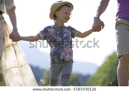 Young girl holding hands with parents