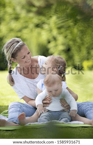 Mother holding daughter and son in park