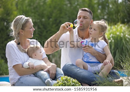 Father blowing bubbles with daughter and family